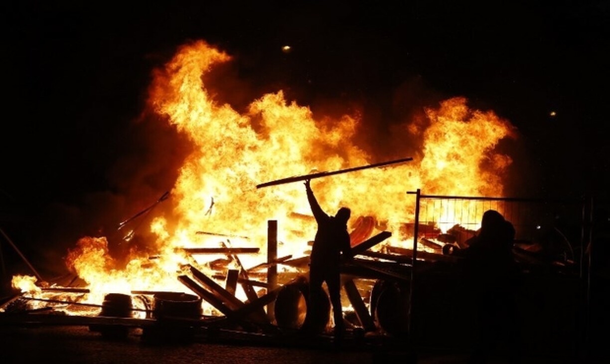 Un manifestant jette un panneau de signalisation dans un feu sur les Champs-Elysées à Paris le 24 novembre 2018.
