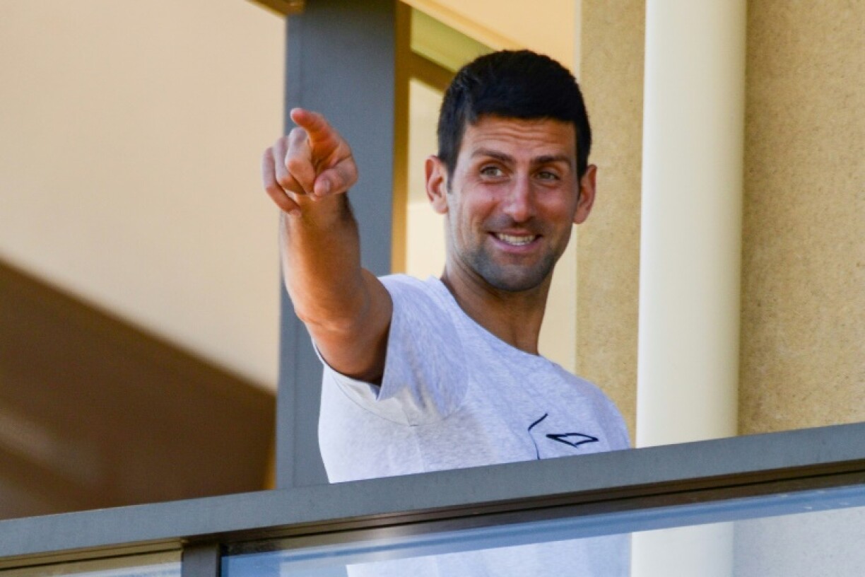 N.1 mondial, le Serbe Novak Djokovic salue les photographes depuis le balcon de sa chambre d'hôtel à Adelaïde, le 18 janvier 2021