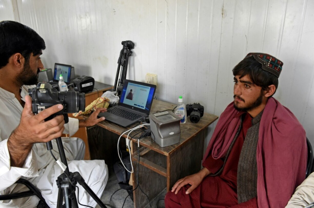 An Afghan refugee (R) provides biometric verification at a holding centre near the Pakistan-Afghanistan border