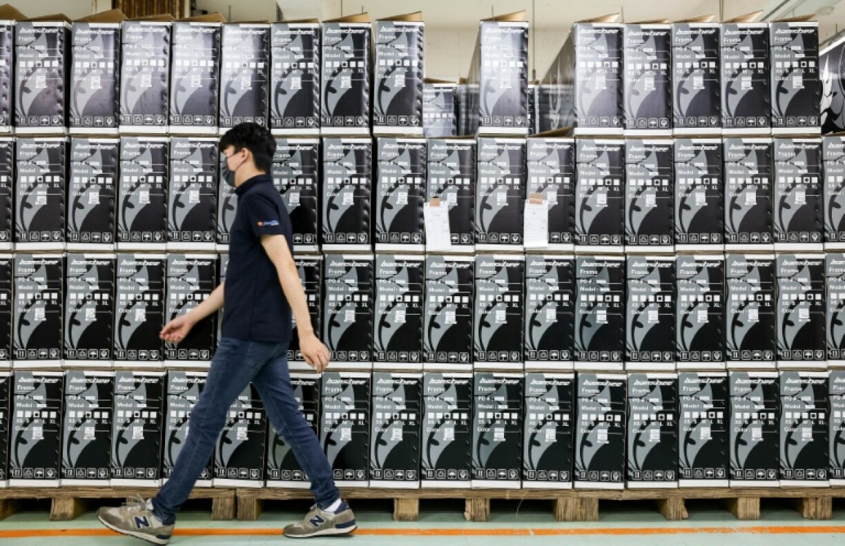 A worker walks past boxes of fold-up bicycles mostly destined for Europe and Asia at a factory of Pacific Cycles in Taoyuan on April 30, 2025
