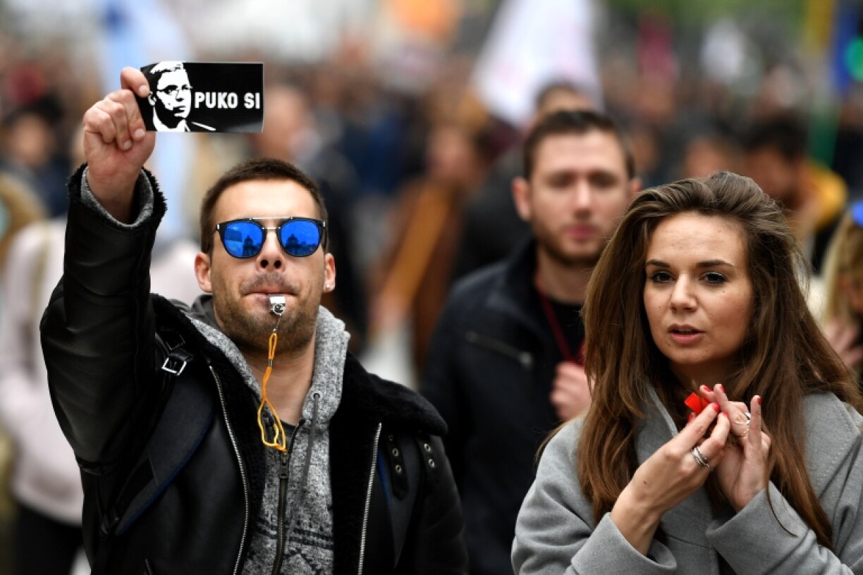 A protester holds a sticker, showing Serbian Prime Minister Aleksandar Vucic and reading 'You are finished'