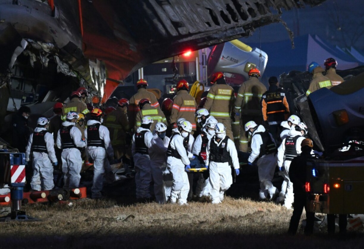 Firefighters and rescue personnel carry the body of a victim from the crash site