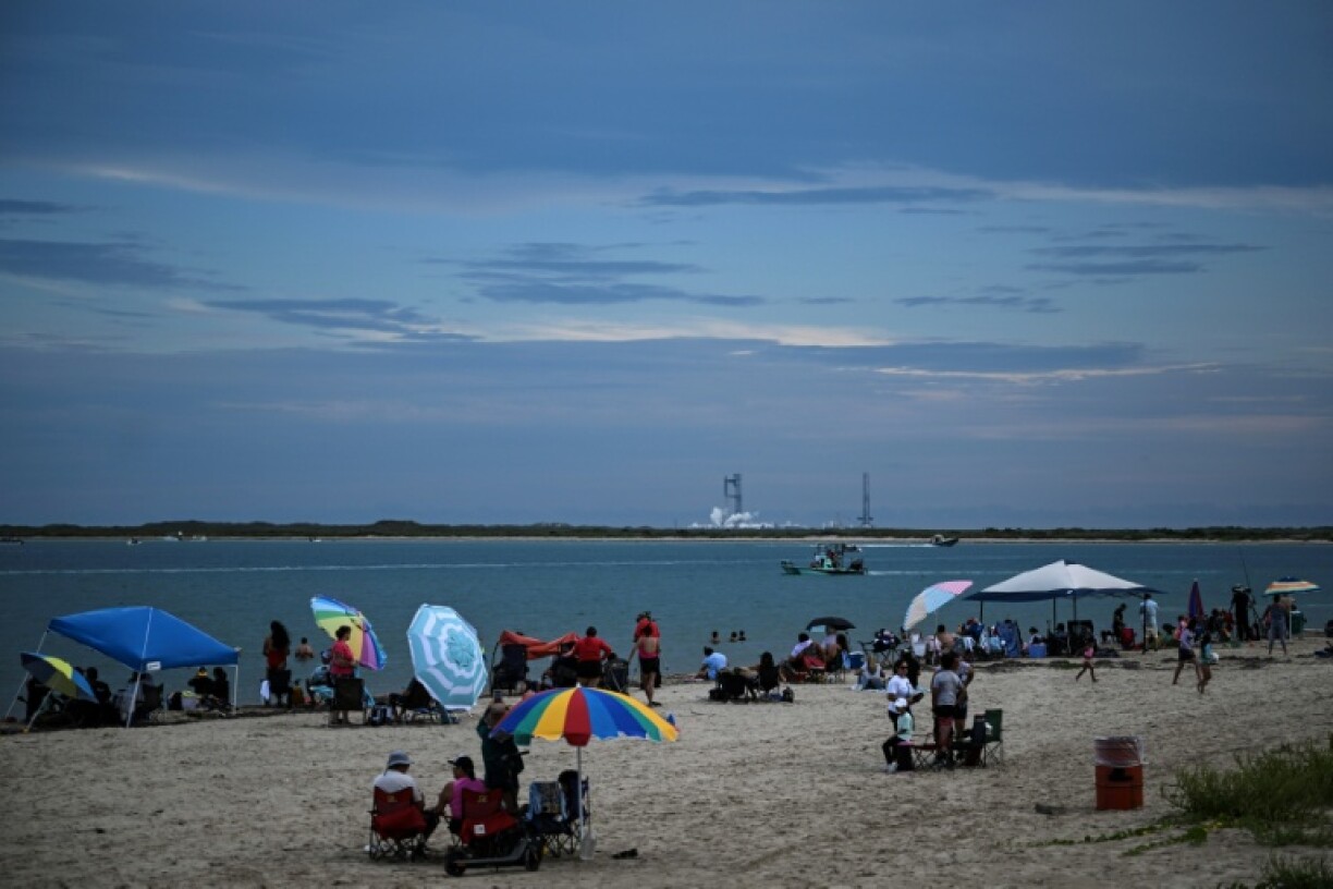 People sit on the beach in South Padre Island, Texas, preparing to watch the scrubbed launch