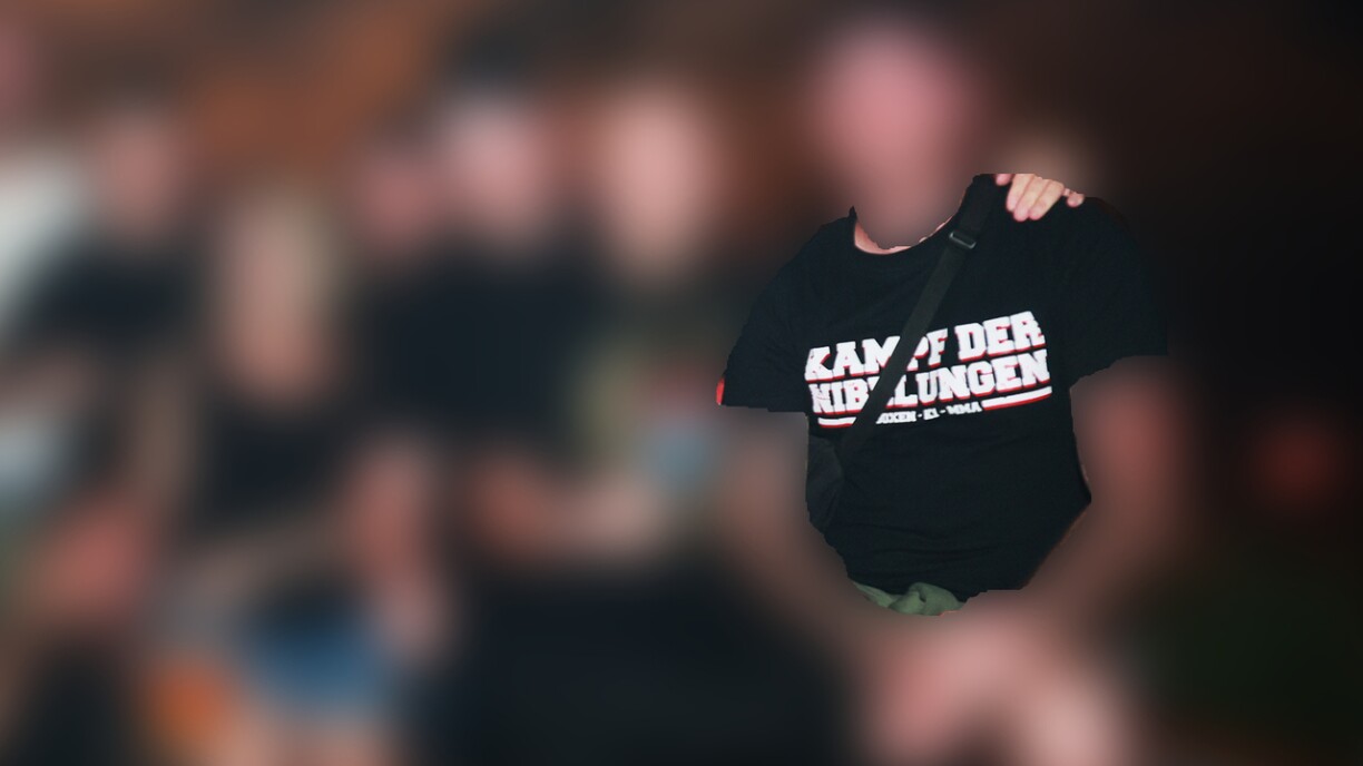 Op enger Gruppefoto war eng Persoun ze gesinn, déi en T-Shirt mam Schrëftzoch