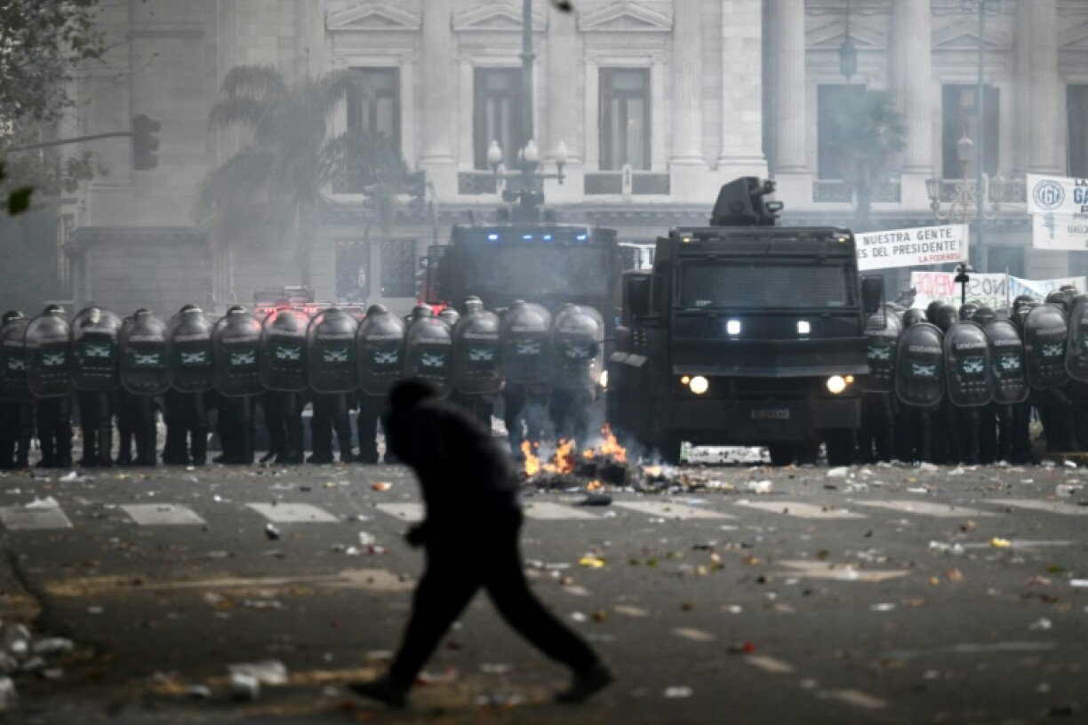 Un manifestant devant une un cordon de police lors des manifestations devant le parlement argentin, à Buenos Aires le 12 juin 2024