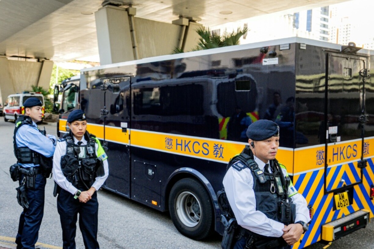 Des policiers surveillent un fourgon des services pénitentiaires transportant l'ex-magnat des médias Jimmy Lai à sa sortie du tribunal de West Kowloon après l'énoncé du verdict dans son procès pour atteinte à la sécurité nationale à Hong Kong, le 15 décembre 2025