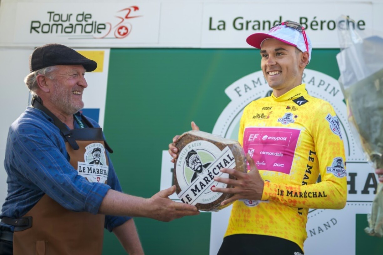 France's Alex Baudin (EF), wearing the overall leader's yellow jersey, receives a cheese as he celebrates during the podium ceremony