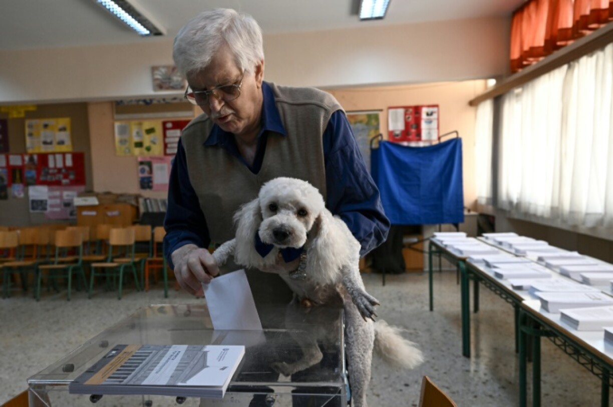 Un électeur portant son chien vote aux législatives, le 21 mai 2023 à Athènes