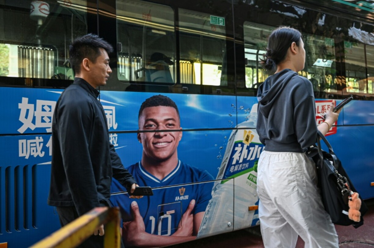 People walk past a bus featuring French football star Kylian Mbappe in Shanghai
