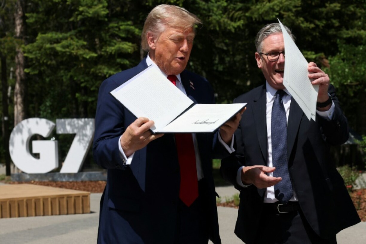 US President Donald Trump holds a signed US-UK trade deal next to British Prime Minister Keir Starmer