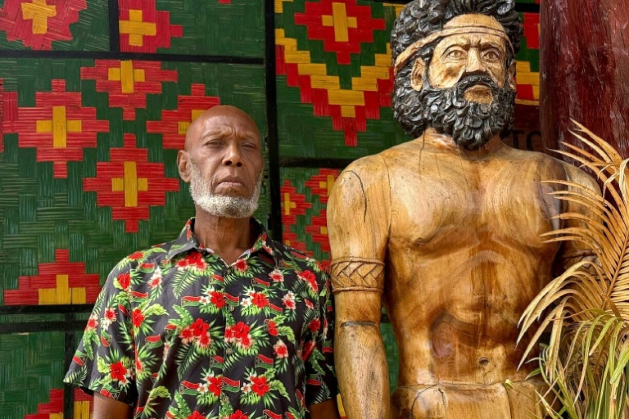 Head chief of the volcanic island of Ambrym, George Bumseng, stands next to a wooden statue in the Vanuatu capital of Port Vila on July 24, 2025