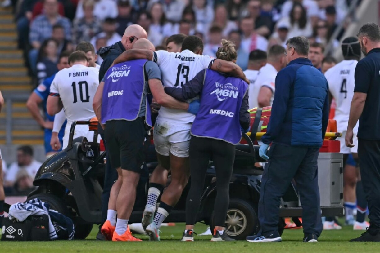 England centre Ollie Lawrence (C) is helped from the field after suffering an Achilles injury during a Six Nations win over Italy at Twickenham