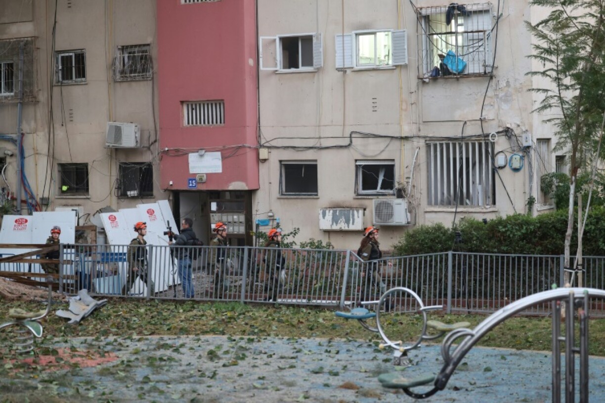 Israeli emergency responders inspect the damage at the site where a projectile fired from Yemen landed in Tel Aviv