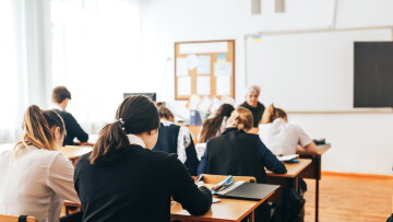 Symbolbild vu Schüler an engem Klassesall.