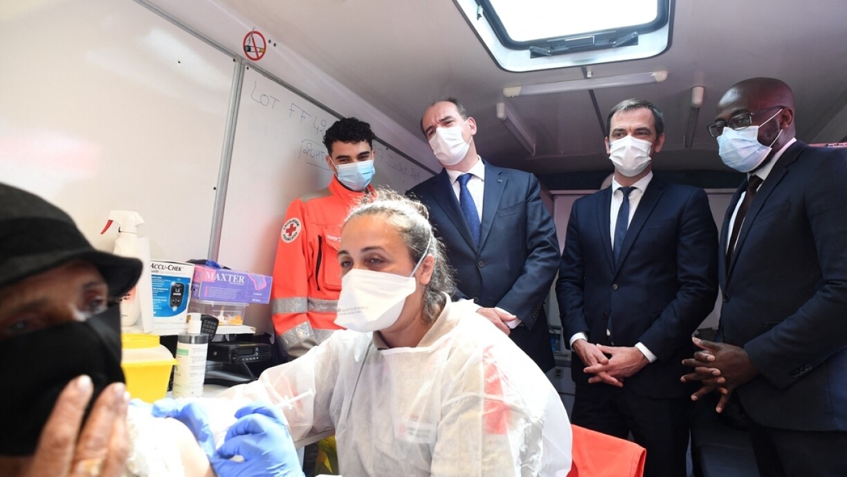 French Health Minister Olivier Veran (2ndR) and French Prime Minister Jean Castex (2ndL) look at a woman receiving a dose of the Pfizer-BioNTech COVID-19 vaccine at a vaccination center in Villetaneuse, northern suburb of Paris, on July 27, 2021.
