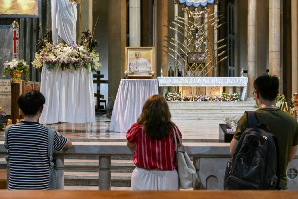 People pray in front of a portrait of Pope Francis after mass in Manila