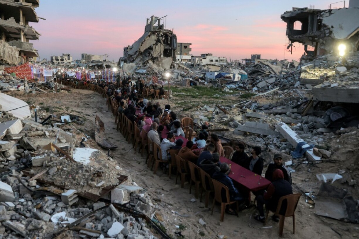 People gather among the rubble of destroyed buildings for a communal iftar fast-breaking meal on the second day of the Muslim holy month of Ramadan in in Gaza City's Tal al-Hawa district