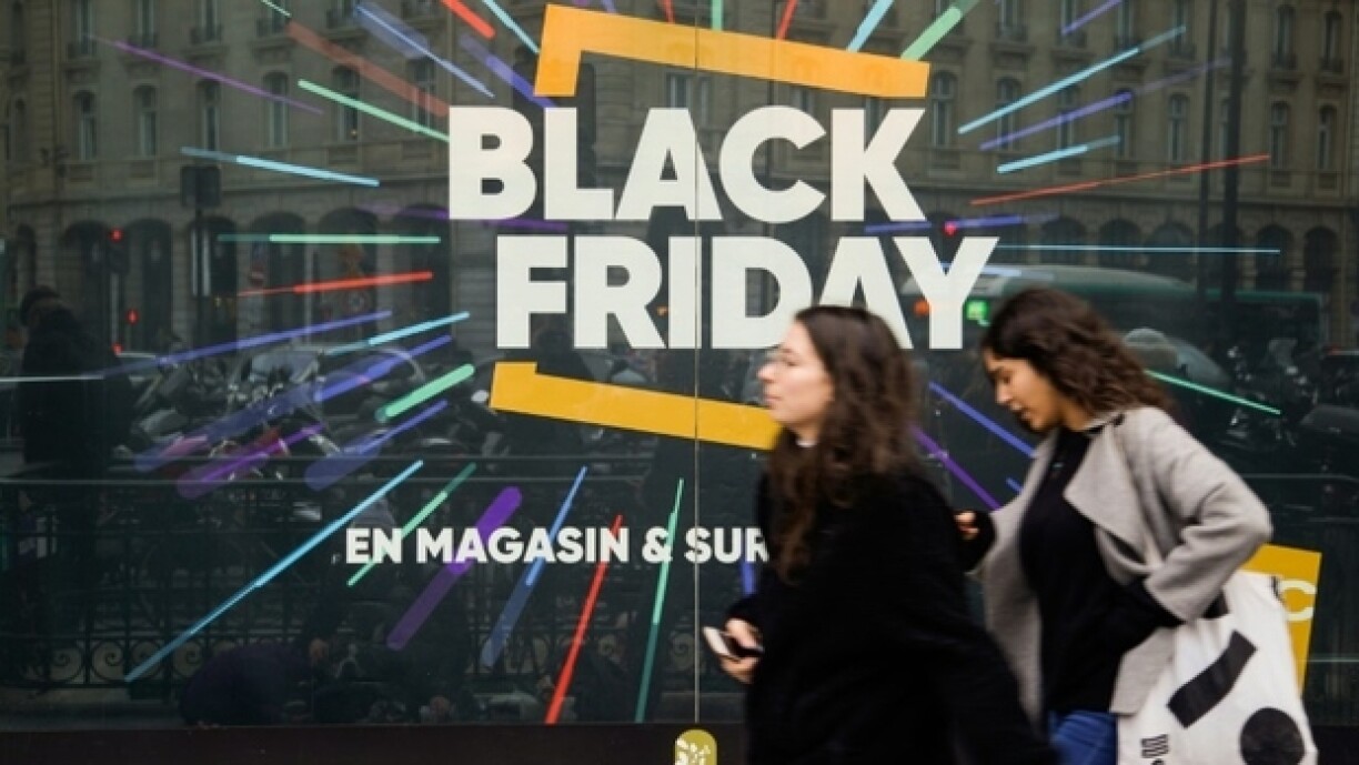 Des passantes marchent devant un panneau annonçant le