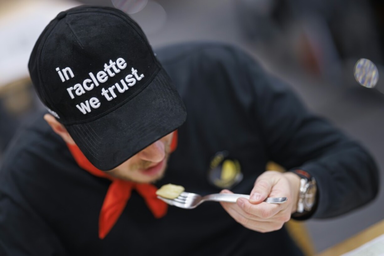 Un juré des premiers championnats du monde de la raclette va goûter un morceau de fromage, à Morgins, en Suisse, le 28 octobre 2023