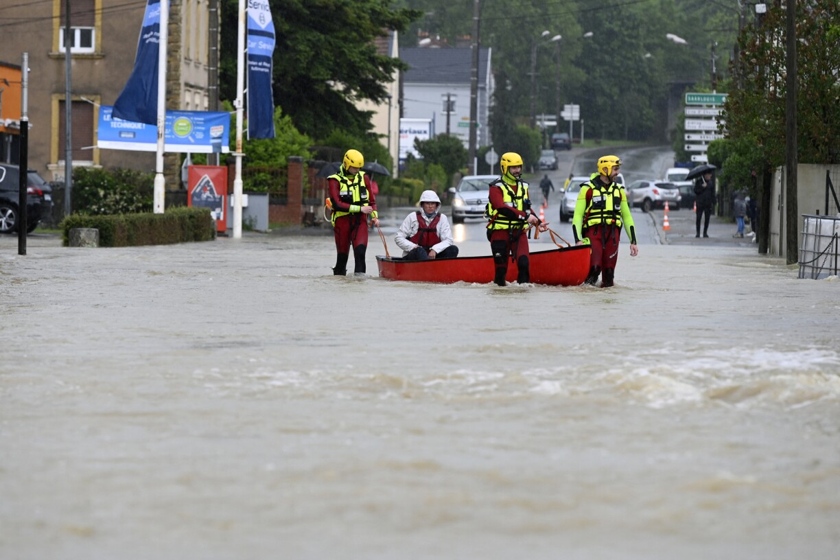Des pompiers aident les résidents de Boulay à traverses une zone inondée le 17 mai 2024