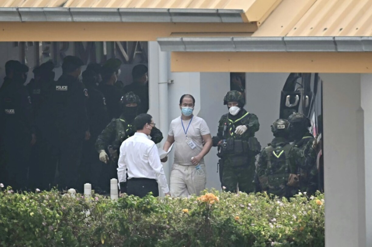 Thai army personnel escort an alleged scam centre worker at a border checkpoint in Mae Sot