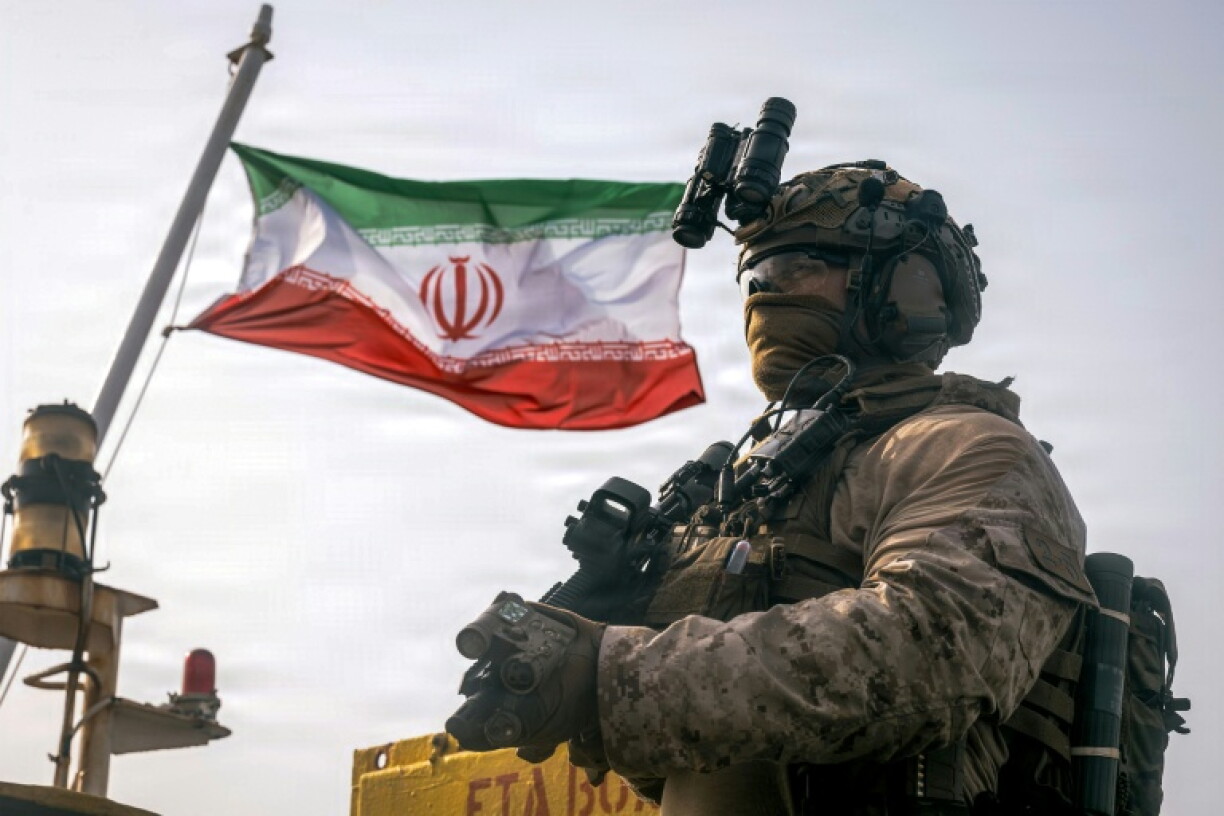Cette image fournie par le corps des Marines américain montre un drpaeau iranien derrière un Marine, lors du contrôle d'un navire dans le Golfe, le 16 juillet 2026.