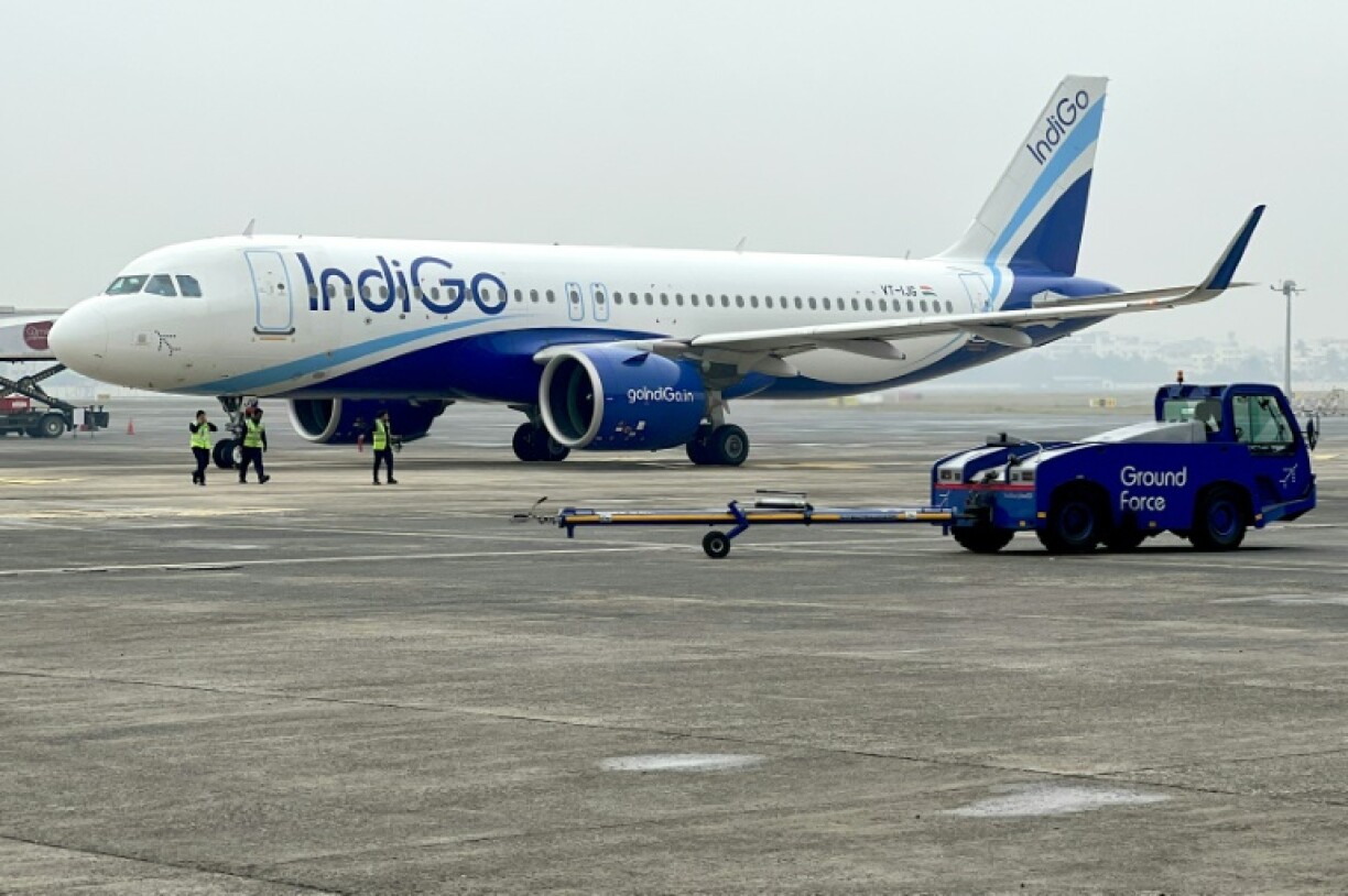 Ground staff walk past an IndiGo airlines aircraft taxiing in the apron at the Netaji Subhash Chandra Bose International Airport in Kolkata in February 2024