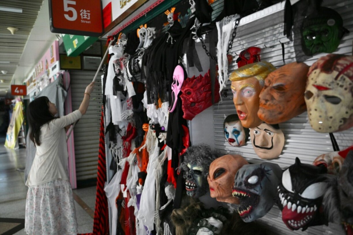 A vendor closes her shop with a face mask of US President Donald Trump at the Yiwu International Trade Market in China on April 11, 2025