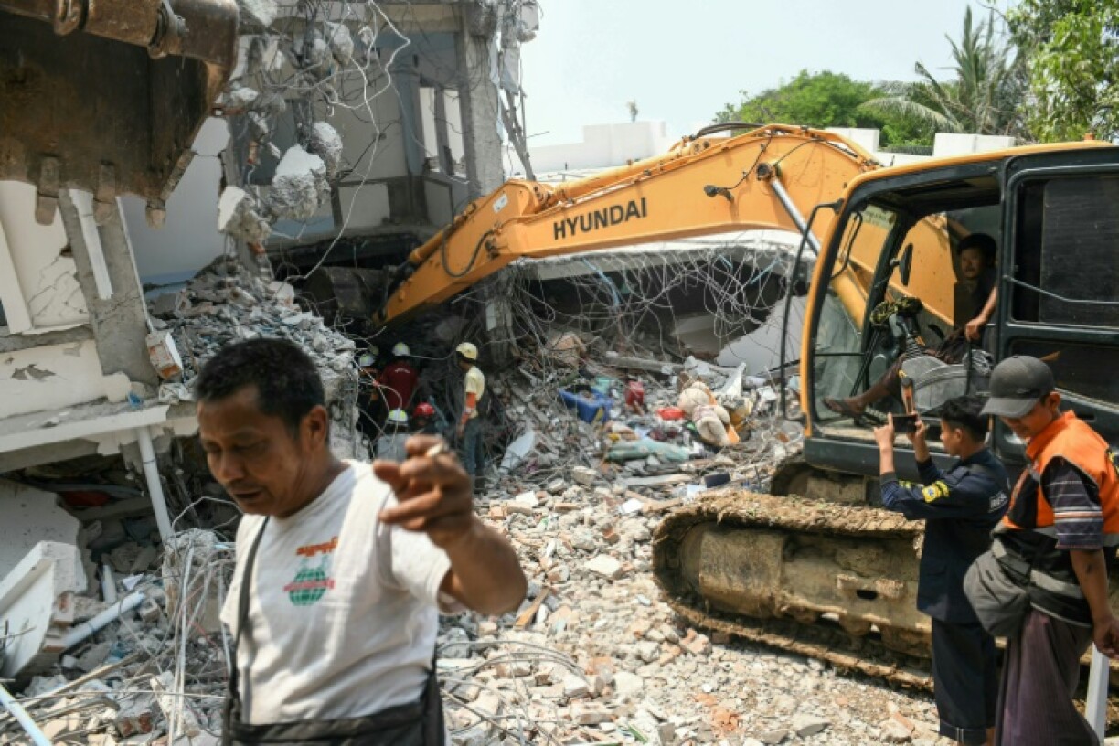 Un engin de chantier utilisé pour fouiller les décombres à la recherche de survivants dans un bâtiment détruit à Mandalay, le 29 mars 2025, au lendemain d'un puissant séisme en Birmanie