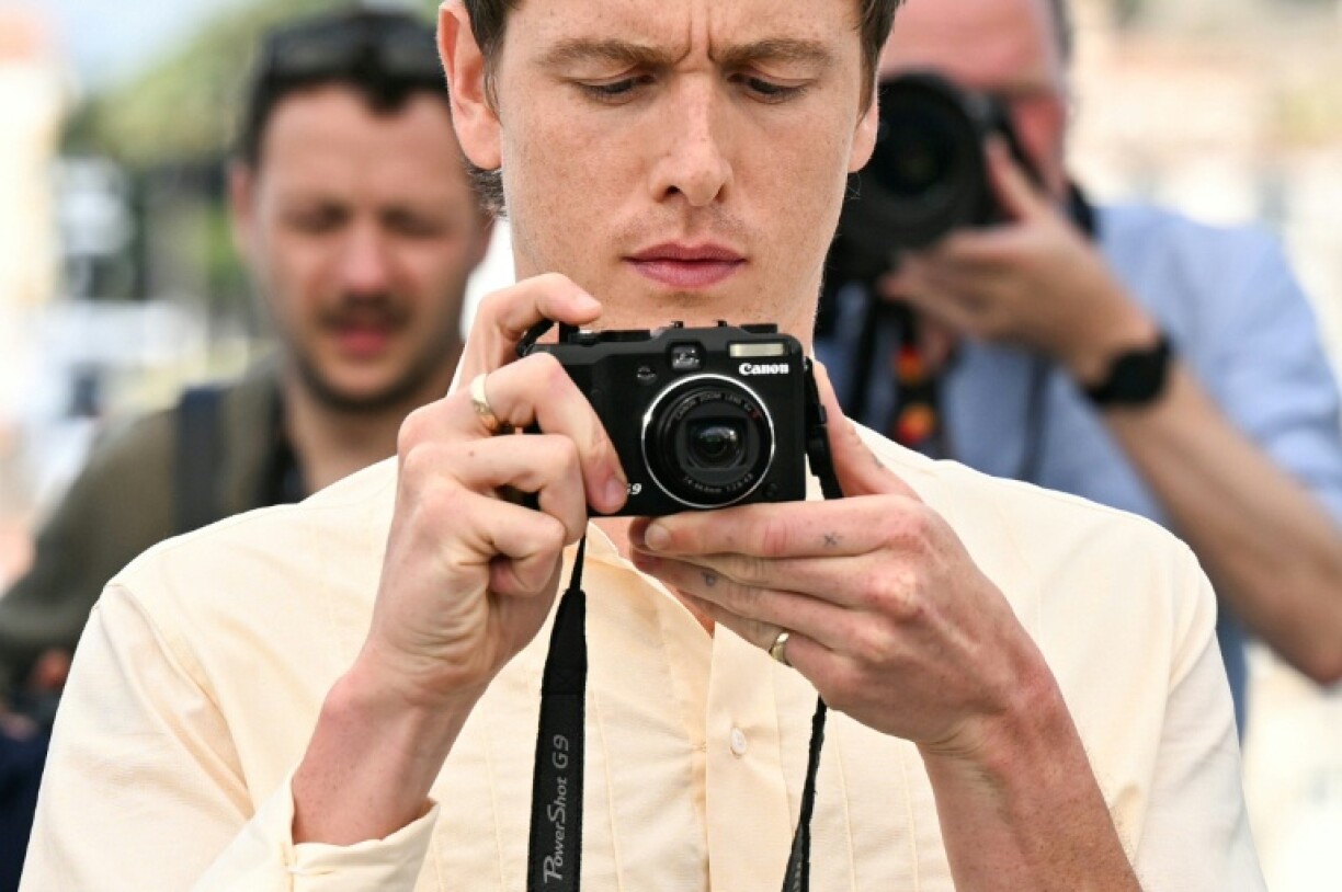 Harris Dickinson takes his own pictures during a photocall for his film
