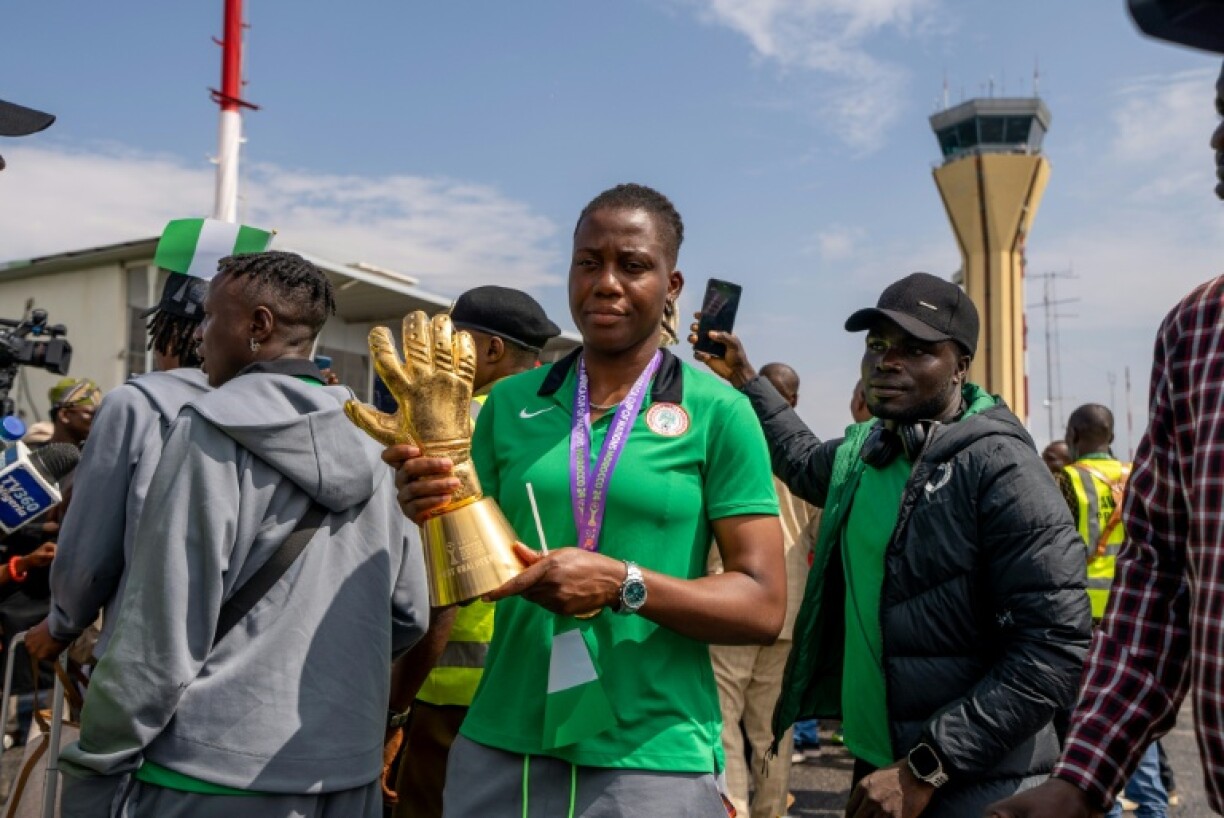 Nigerian goal keeper Chiamaka Nnadozie holds a trophy from the Women's Africa Cup of Nations (WAFCON) as she is welcomed by officials at the Nnamdi Azikiwe International Airport in Abuja