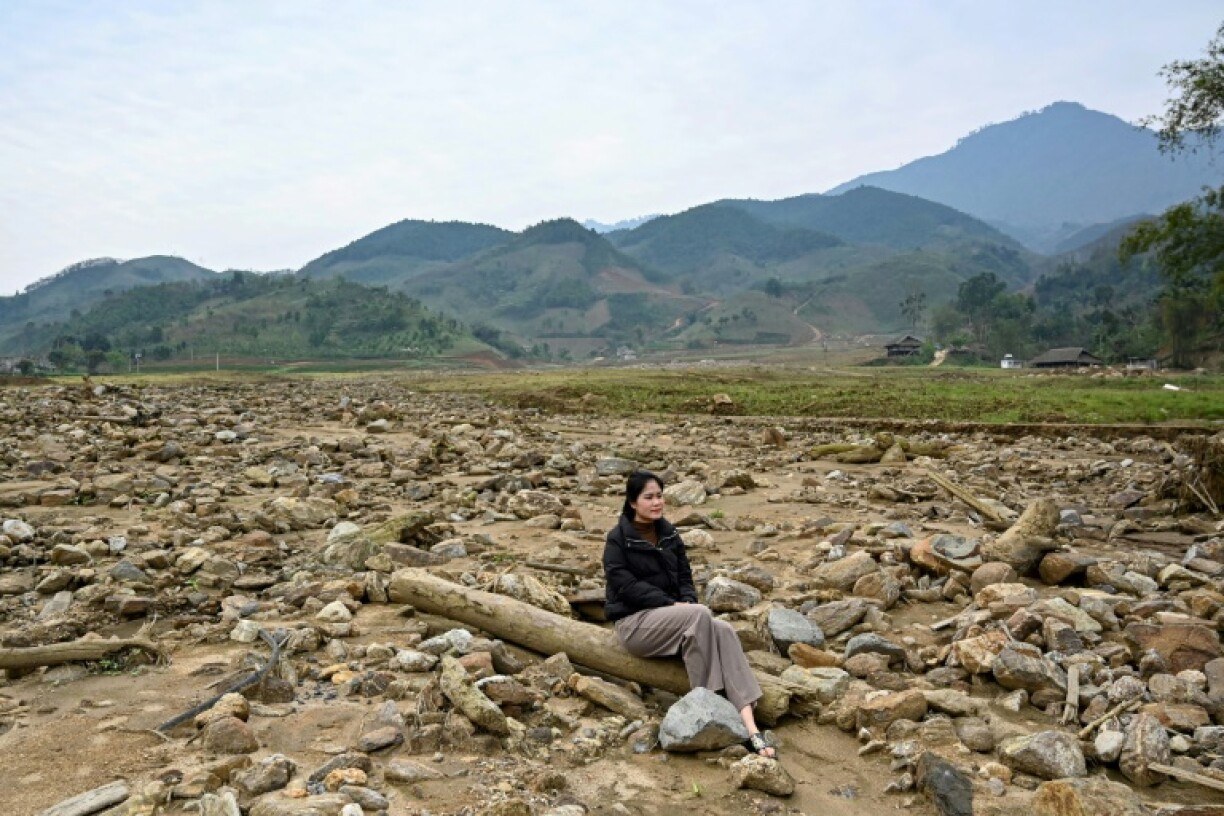Nguyen Thi Kim sitting on a pillar of a destroyed house at the original site of Lang Nu village in Lao Cai province, after part of it was wiped away in a landslide triggered by Typhoon Yagi