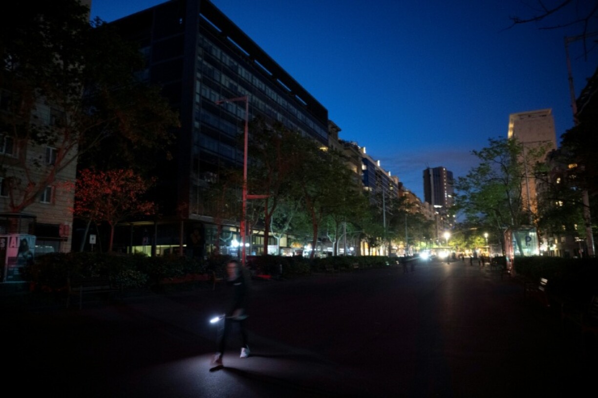 A pedestrian uses a flashlight to walk in a street of Barcelona on April 28, 2025