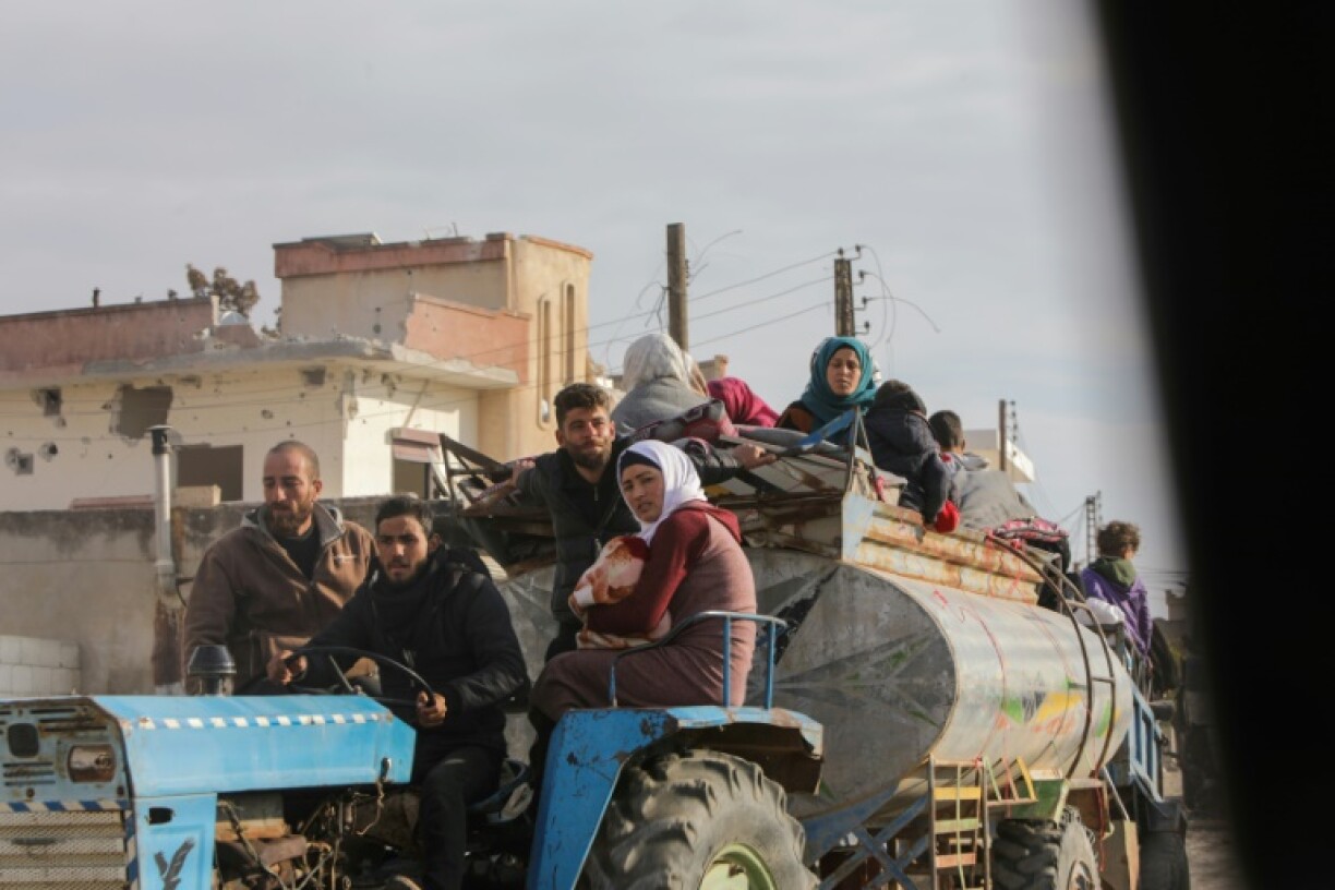 Displaced Syrians drive through Khan Shaykhun town as they flee the Hama area