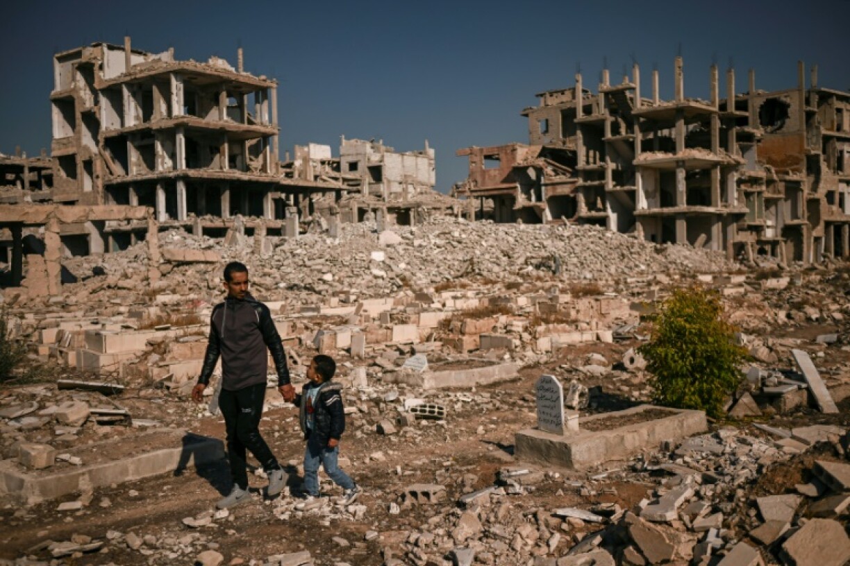 People look for graves of relatives in a damaged cemetery at the Yarmuk Palestinian refugee camp south of Damascus