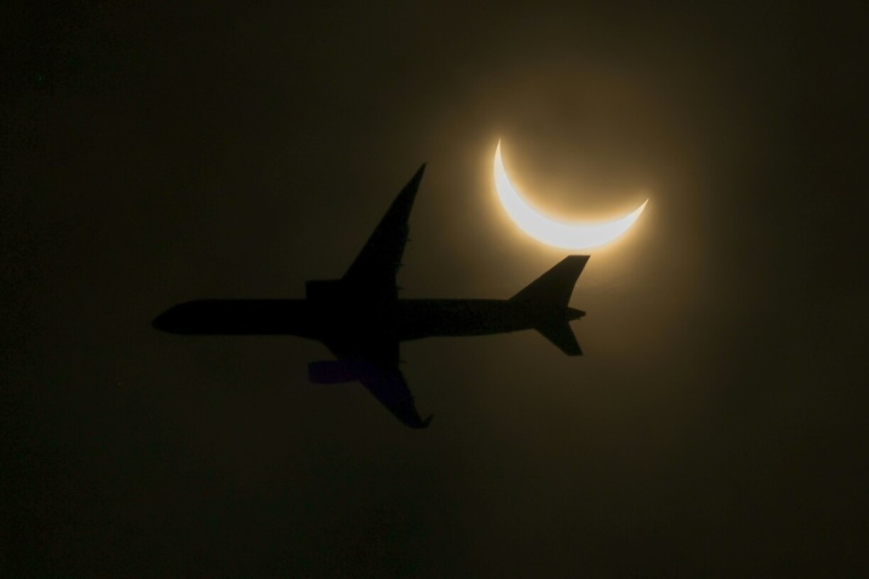 An airplane flies past a partial solar eclipse on April 8, 2024