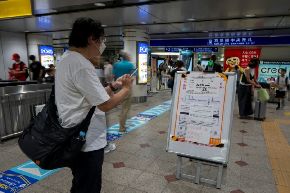 A man checks a notice indicating that some Japanese trains are suspended due to a tsunami warning at Yokohama station, Kanagawa prefecture