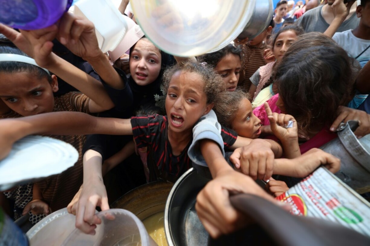 Palestinian children crowded round to receive a hot meal at a food distribution point in Nuseirat on June 30