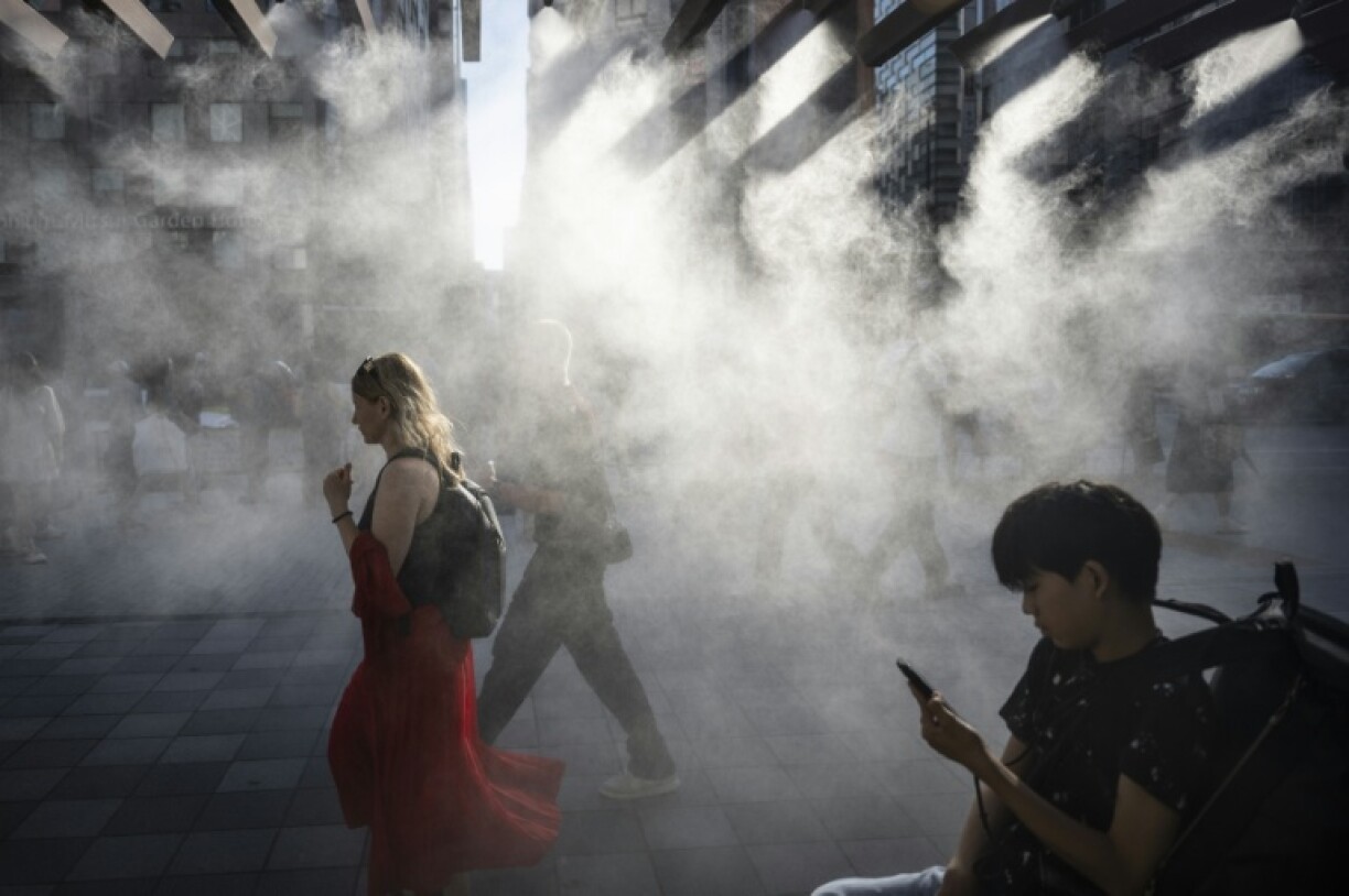 People walk under a misting system on a hot day in Tokyo earlier this year, which is on track to become one of the hottest in recorded history, according to the UN