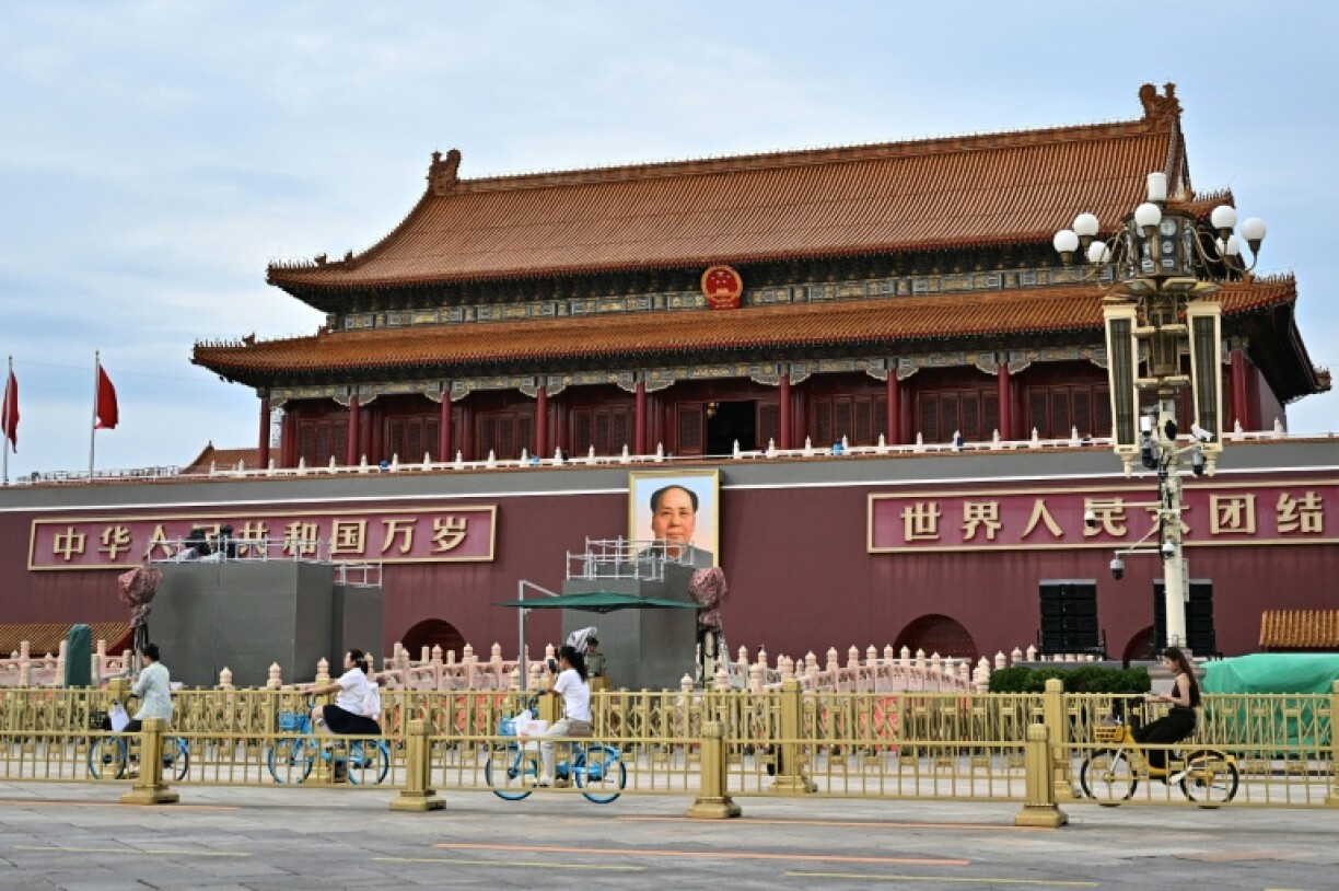 People ride past a portrait of the late communist leader Mao Zedong on Tiananmen Square, where the next military parade will take place on September 3 to mark the 80th anniversary of victory over Japan and the end of World War II