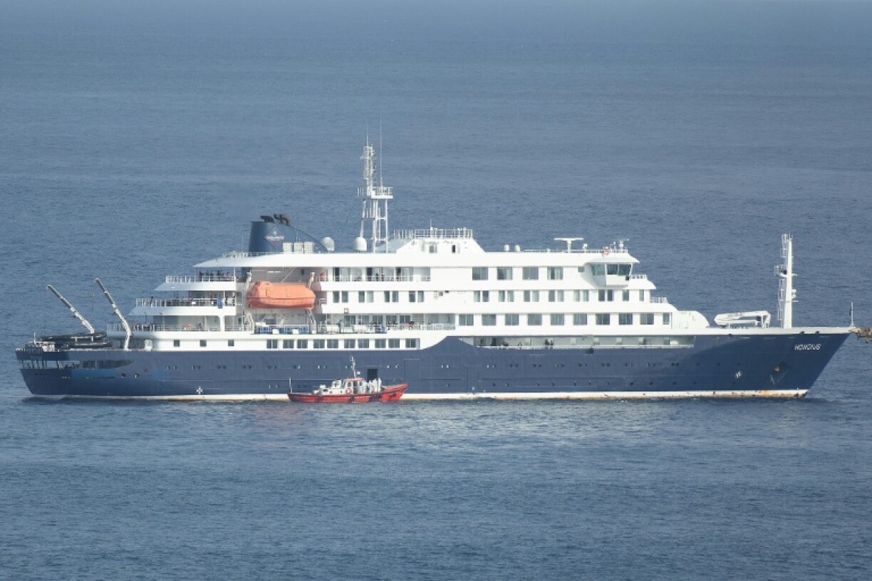 Un bateau-ambulance transportant des membres d'équipage en combinaisons de protection, s'approche du bateau de croisière MV Hondius, au mouillage au large du port de Praia, le 5 mai 2026 au Cap-Vert