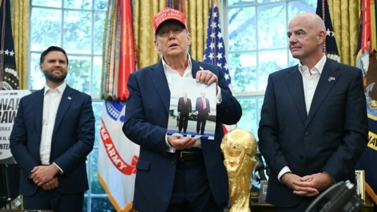Le président américain Donald Trump, entouré du vice-président JD Vance et du chef de la FIFA Gianni Infantino, montre une photo sur laquelle il figure en compagnie de son homologue russe Vladimir Poutine, le 22 août 2025 à la Maison Blanche