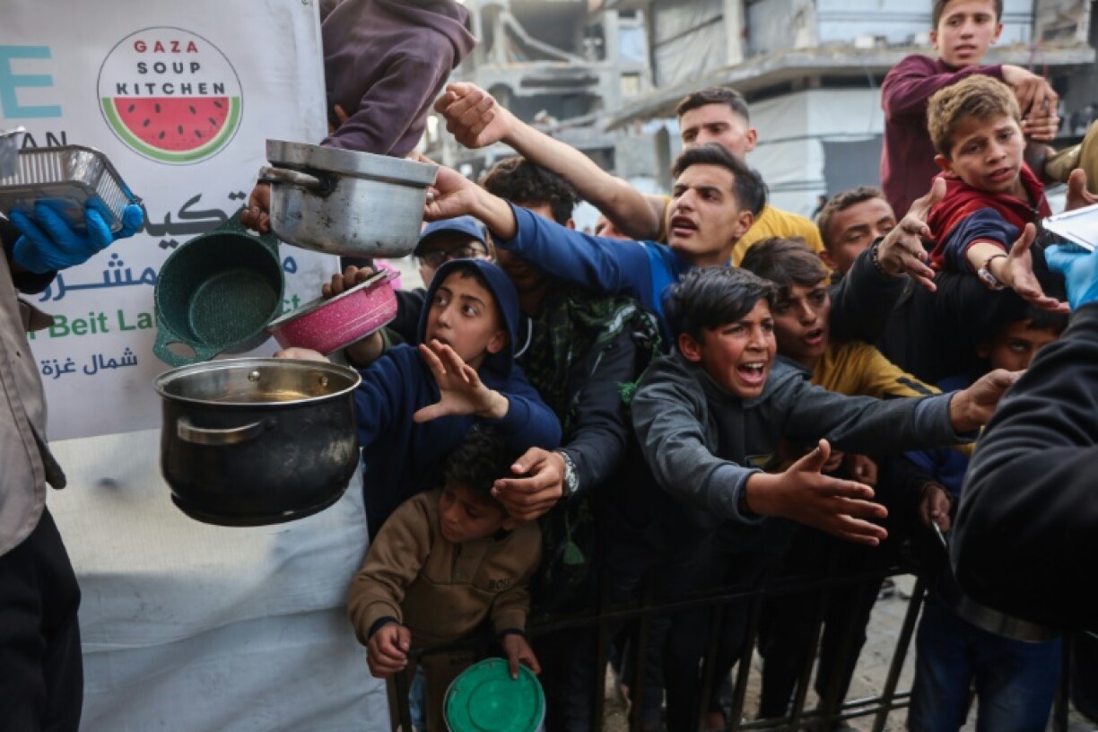 Displaced Palestinian children push into a queue to get a portion of cooked food from a charity in the northern Gaza Strip