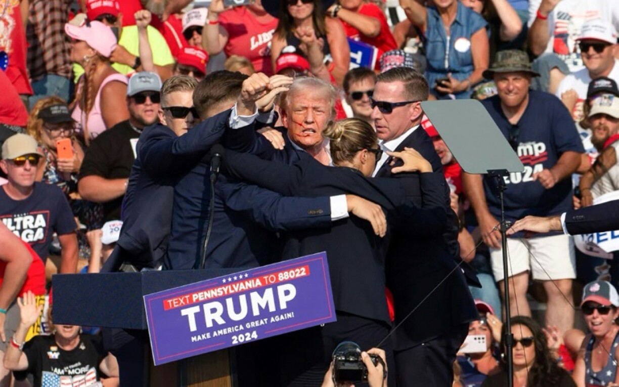 Donald Trump lève le poing en l'air au moment d'être évacué de son meeting à Butler, aux Etats-Unis, le 13 juillet 2024