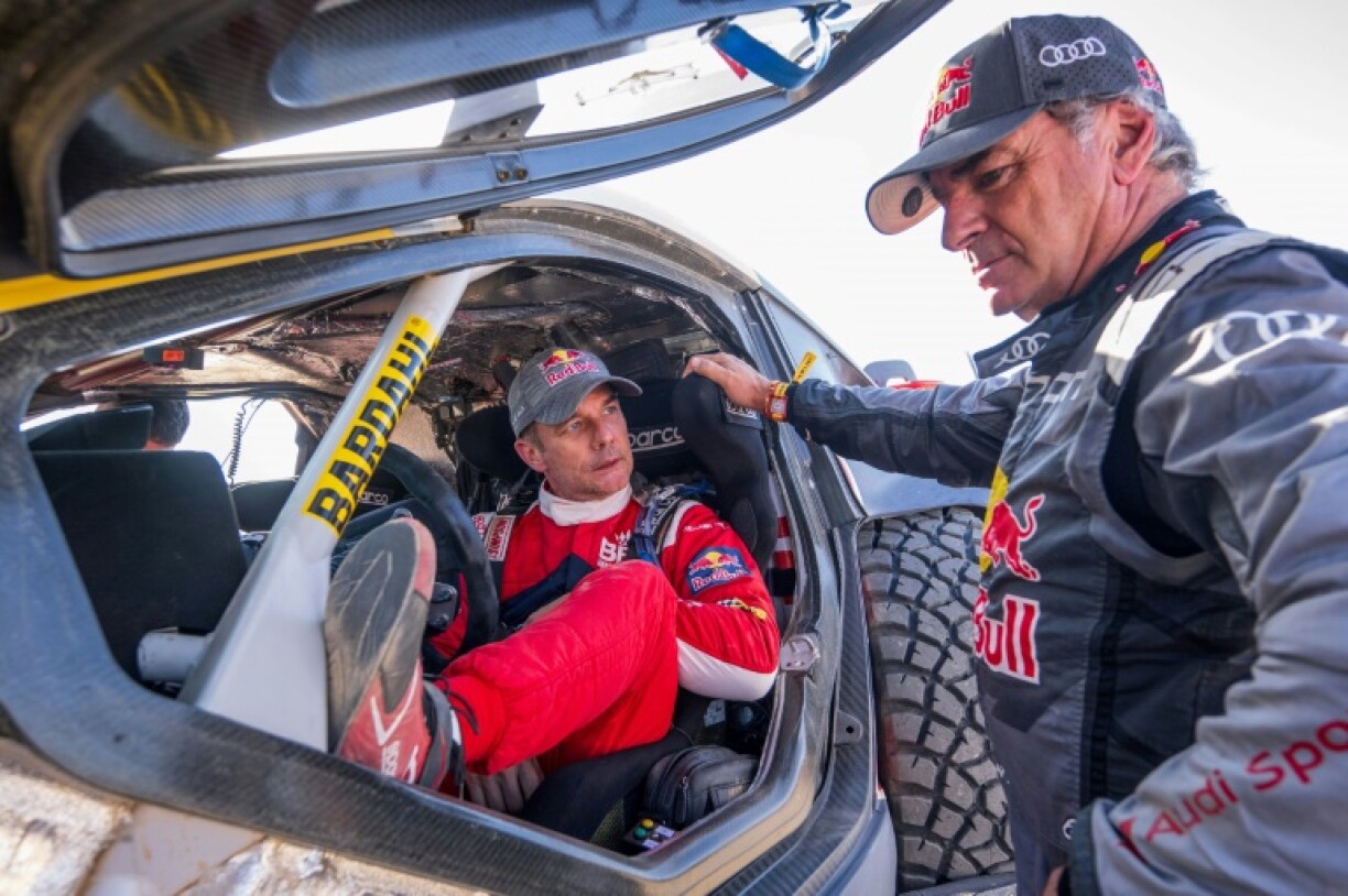 Sébastien Loeb dans son Hunter-BRX de l'écurie Prodrive discute avec le pilote Audi Carlos Sainz le 8 janvier 2024 à la fin de l'étape 3 du Dakar 2024 entre Al Duwadimi et Al Salamiya en Arabie saoudite