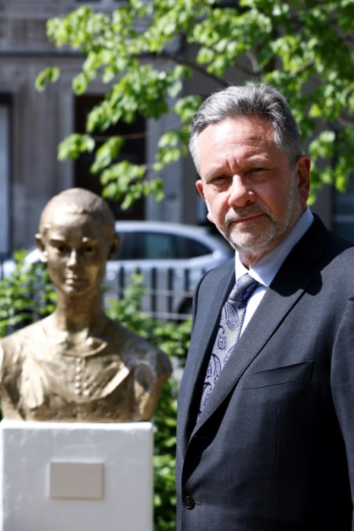 Le fils d'Audrey Hepburn, Sean Hepburn Ferrer, pose à côté du buste de sa mère dans le square qui porte désormais le nom de la star à Bruxelles, le 4 mai 2022
