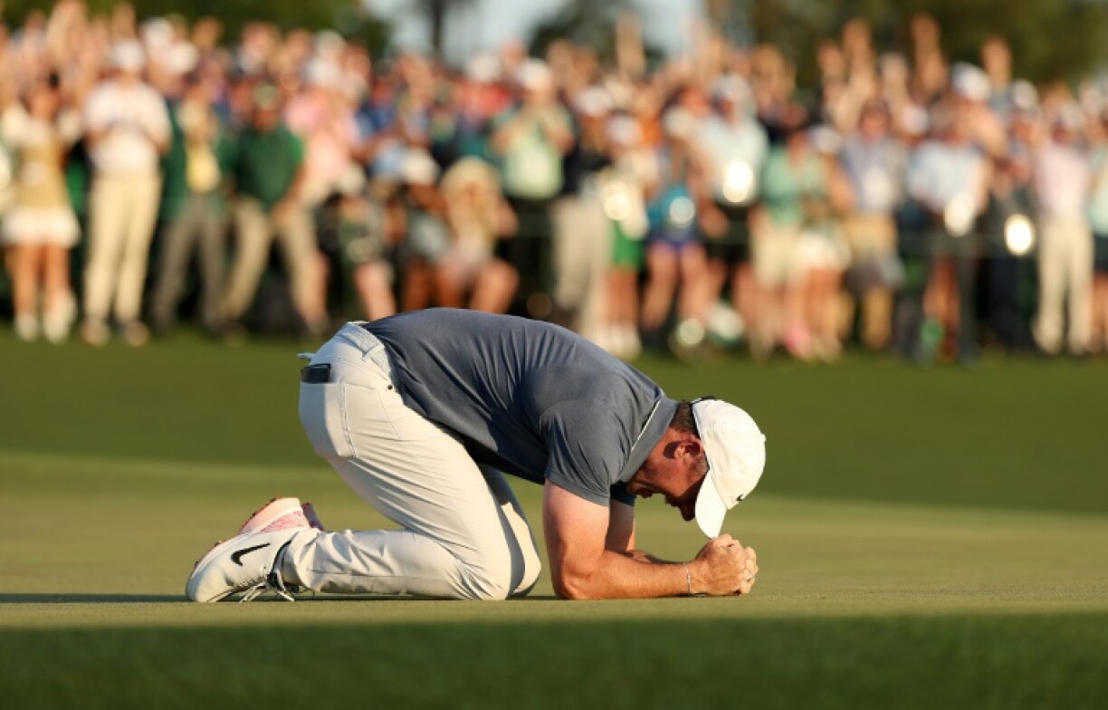 Rory McIlroy of Northern Ireland kneels down and cries on the 18th green after winning the Masters to complete a career Grand Slam
