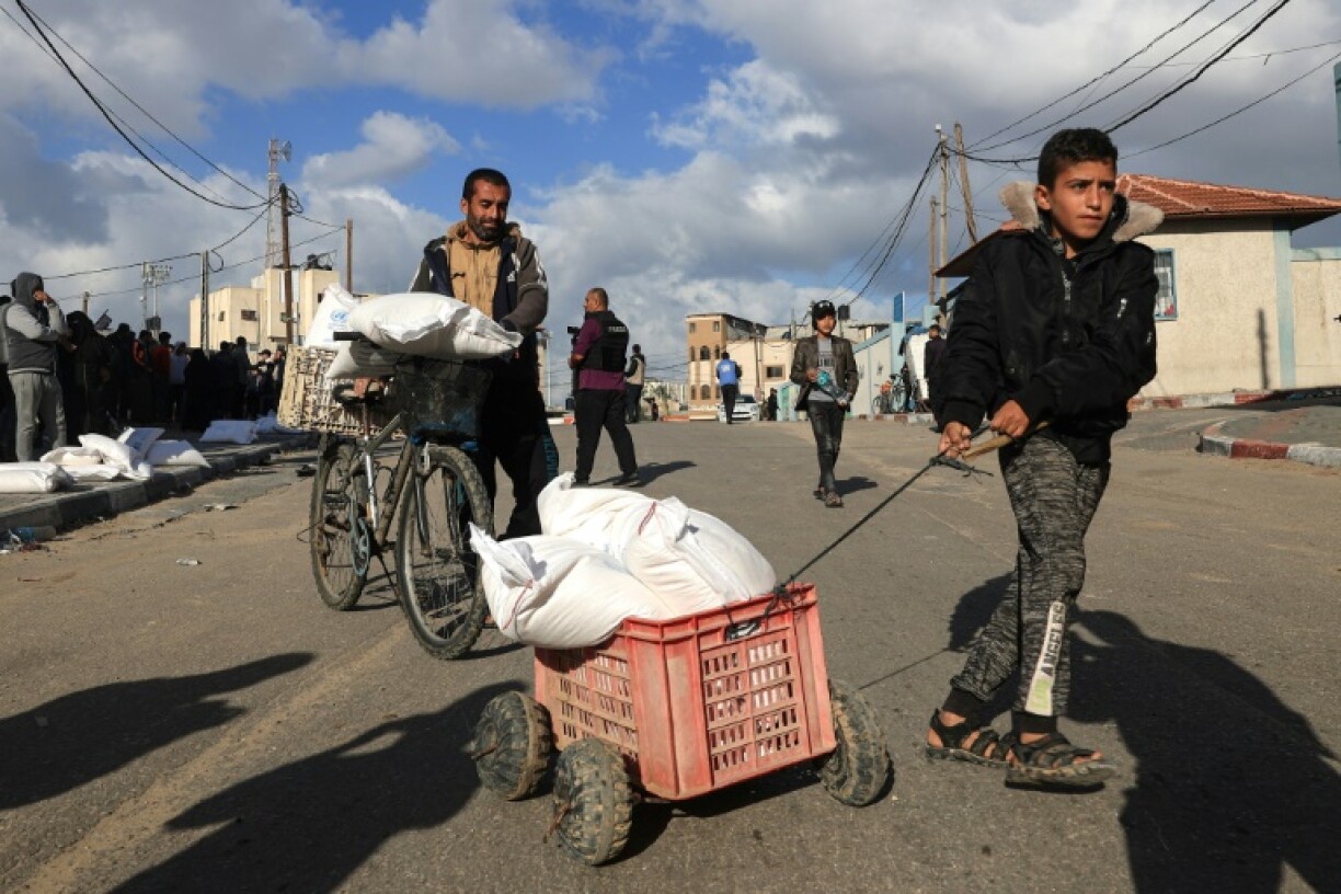 Des Palestiniens reçoivent des sacs de farine au centre de distribution de l'Unrwa du camp de réfugiés de Rafah, dans le sud de la bande de Gaza, le 21 novembre 2023