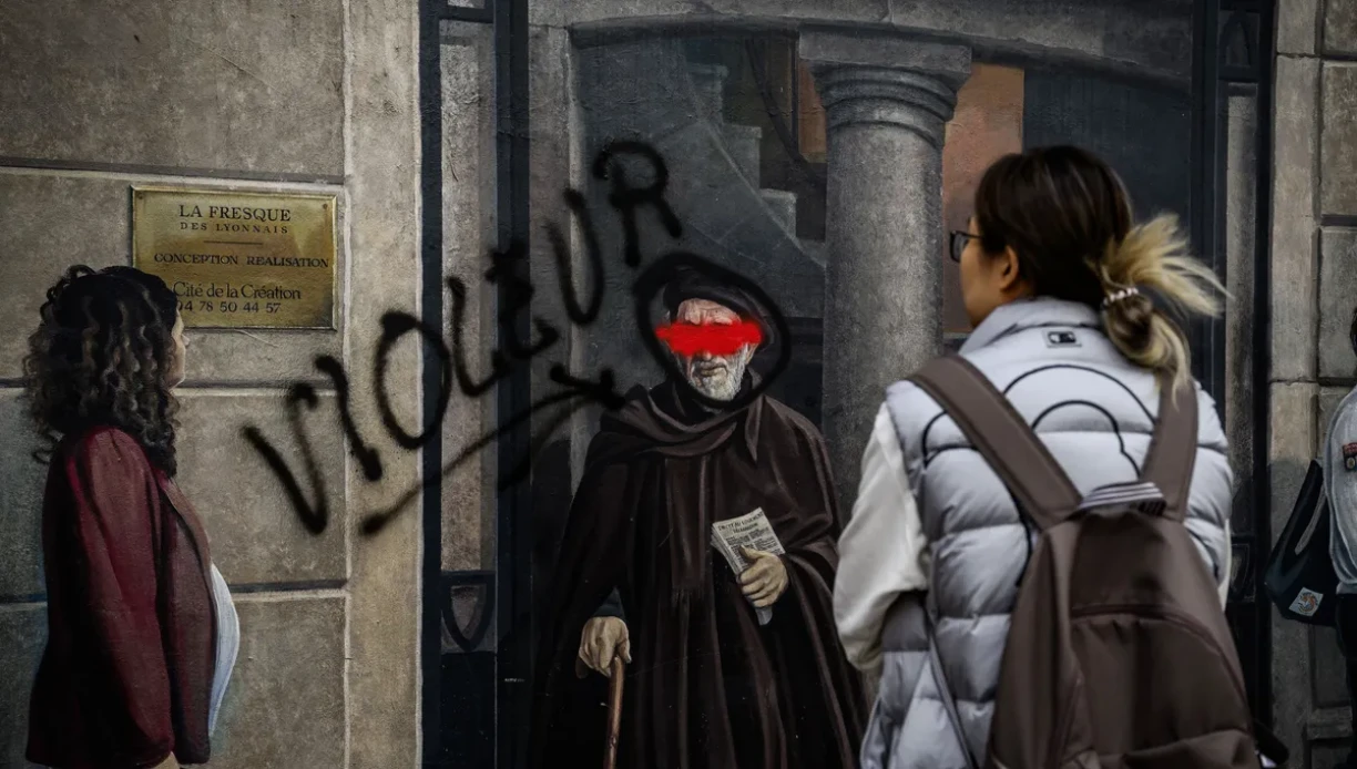 A Lyon, une passante regarde la fresque représentant l'Abbé Pierre avec le mot "violeur", le 30 septembre 2024