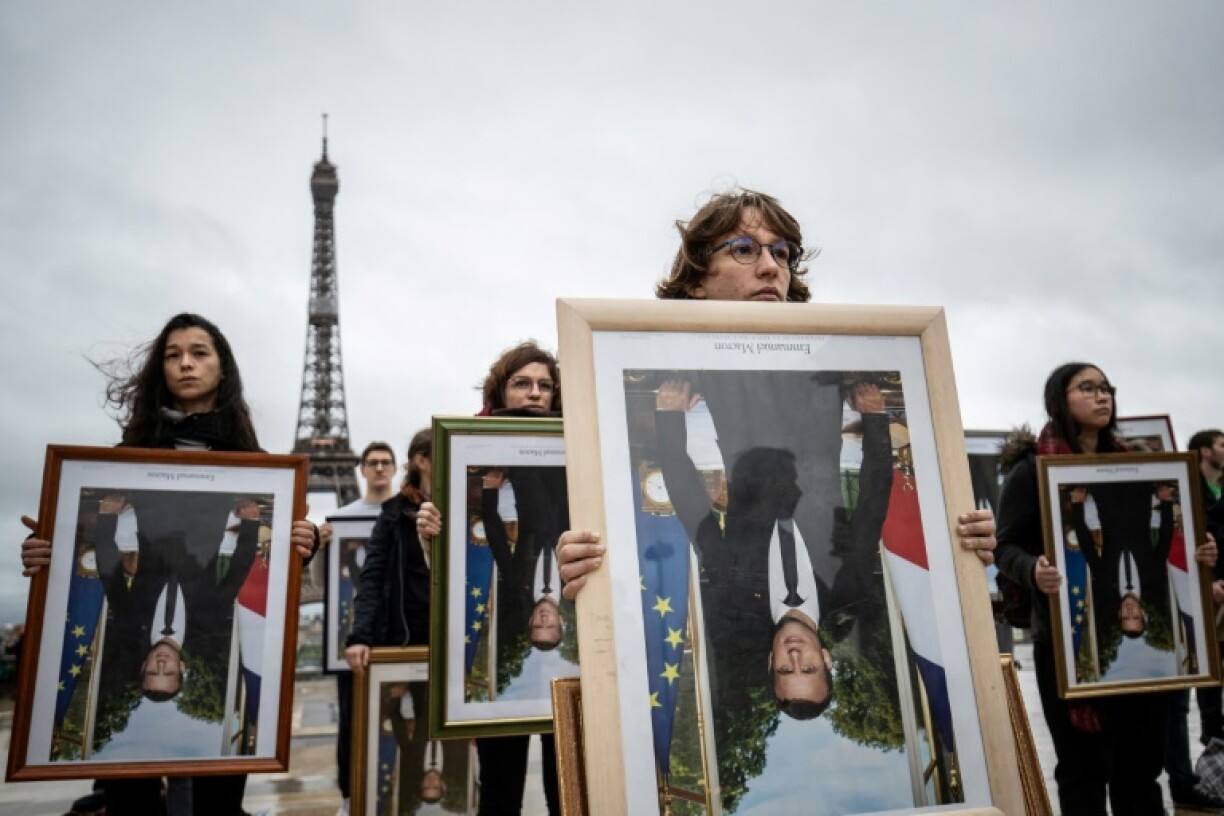 Protesters hold upside-down portraits of the president in 2019